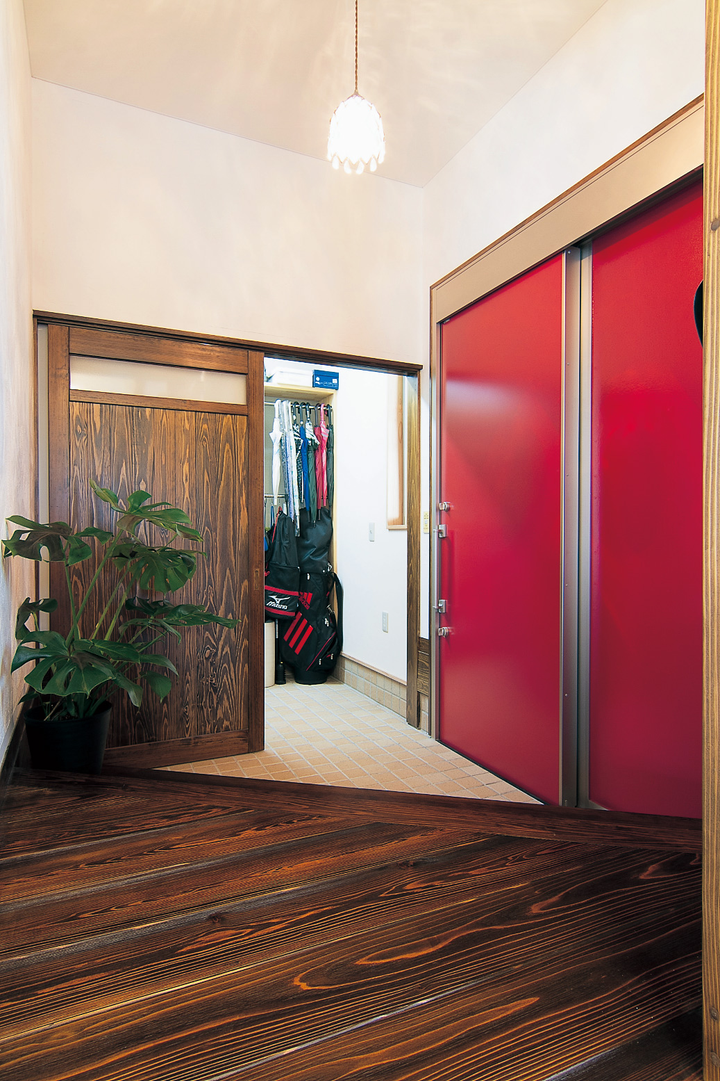 真っ赤なスライドドアが印象的な玄関。ウォークインシューズクロークを通って、直接キッチンへも行ける。ドアの向こうはガレージで濡れずにで切りできて便利